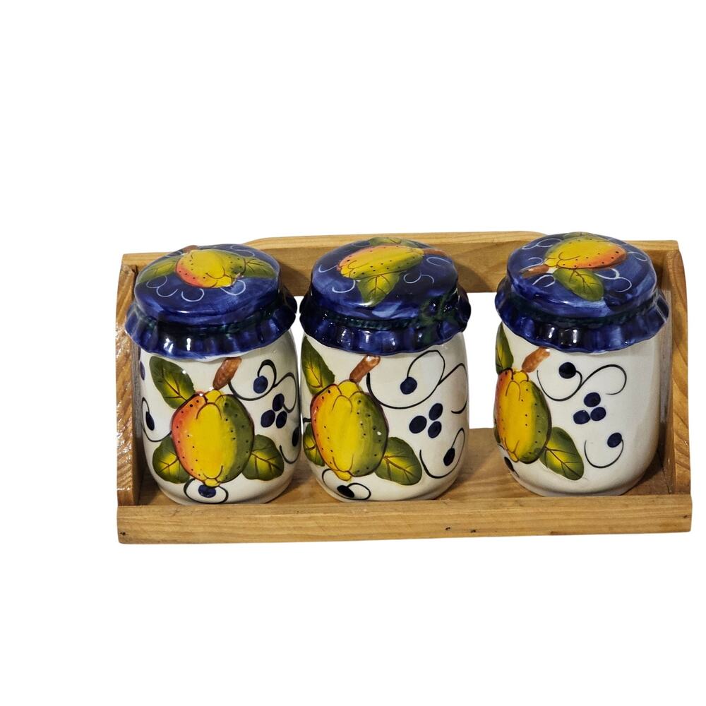 Set of three vintage-style ceramic spice jars with lids and a wooden tray.